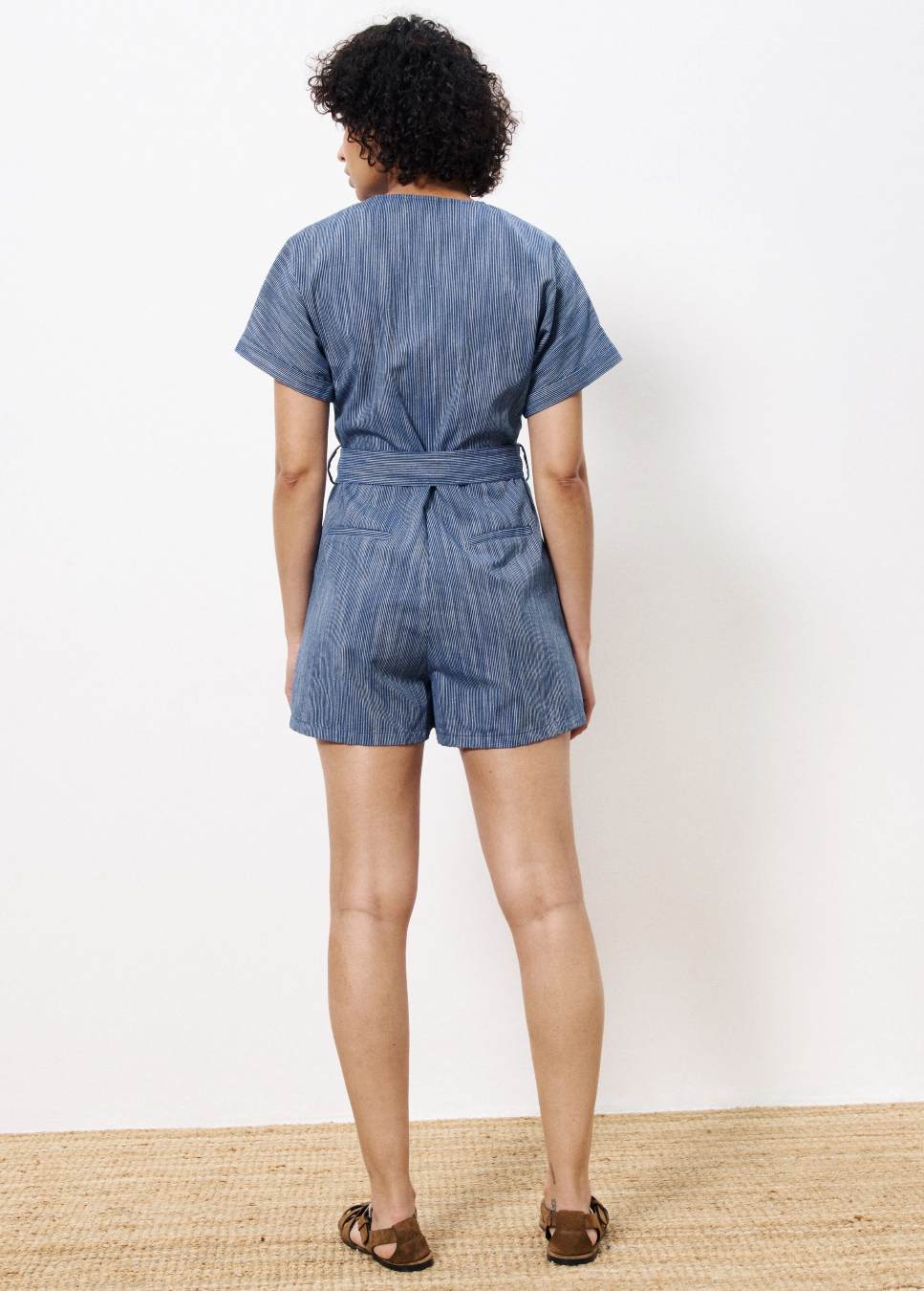 Achterkant van de Adila blauw gestreepte FRNCH playsuit van linnen met een strik en knopen