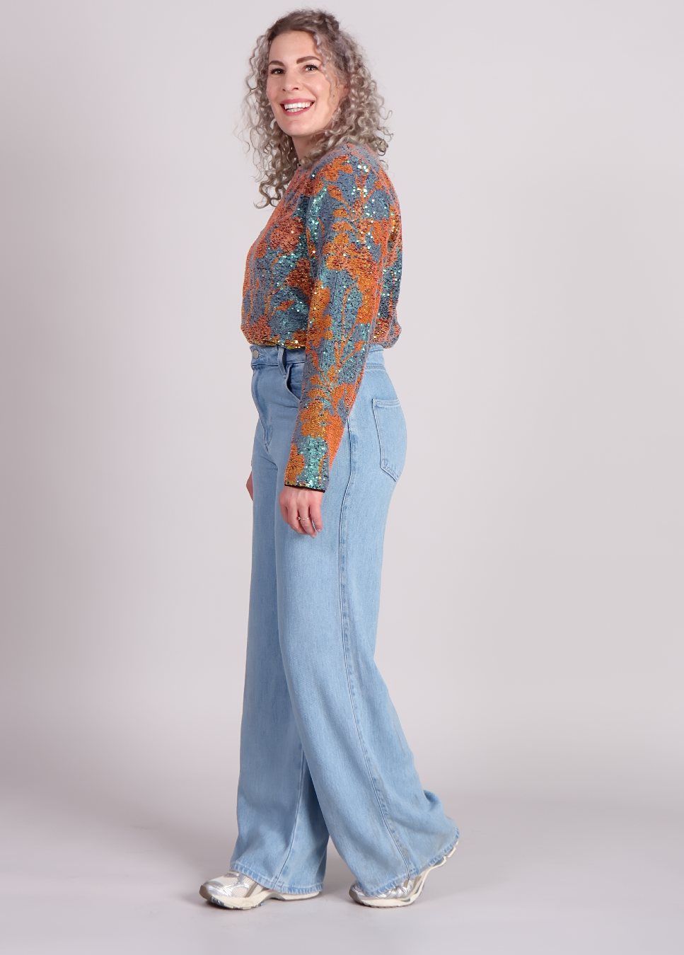 Zijaanzicht van de lio studio amaya top met blauw en gouden pailletten op model